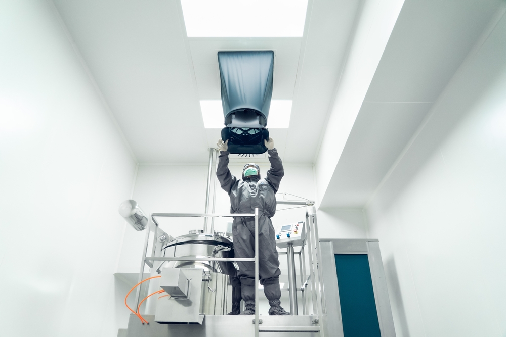 The,Unidentified,Operator,Is,Using,The,Capture,Hood,Balometer,To A person in protective gear lifts a large object in a clean room with bright lighting and stainless steel equipment.