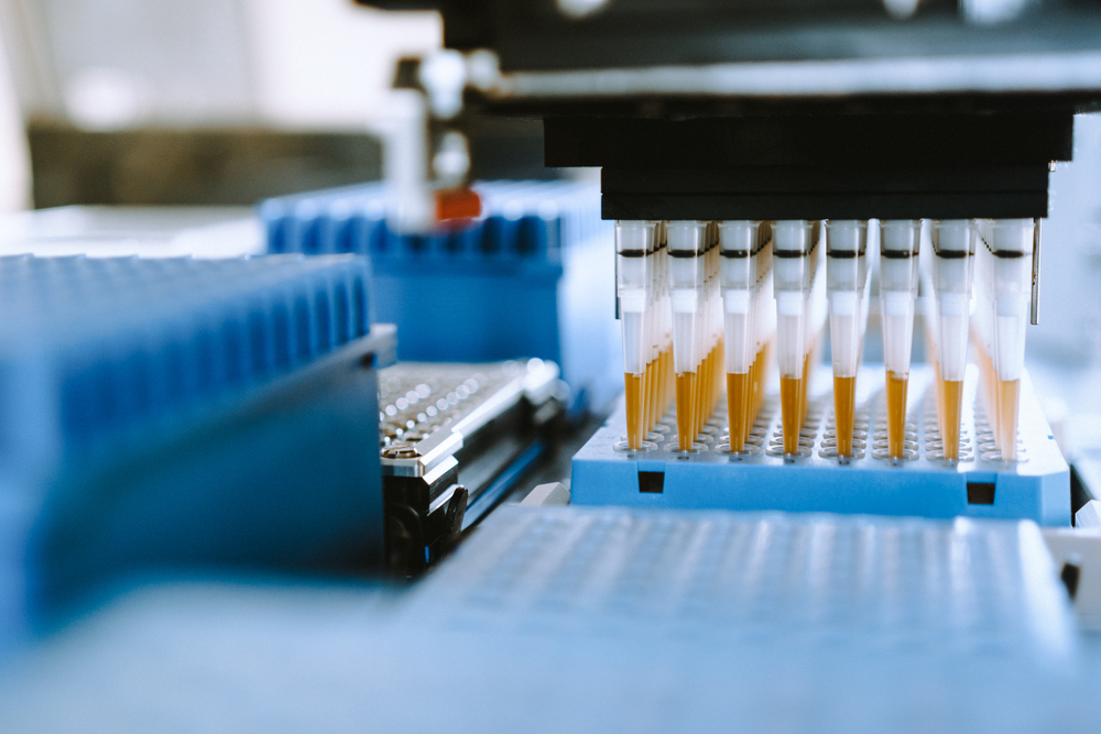 Robotic pipetting station in action, featuring a multi-channel liquid handler and blue tip racks for precise liquid transfers.